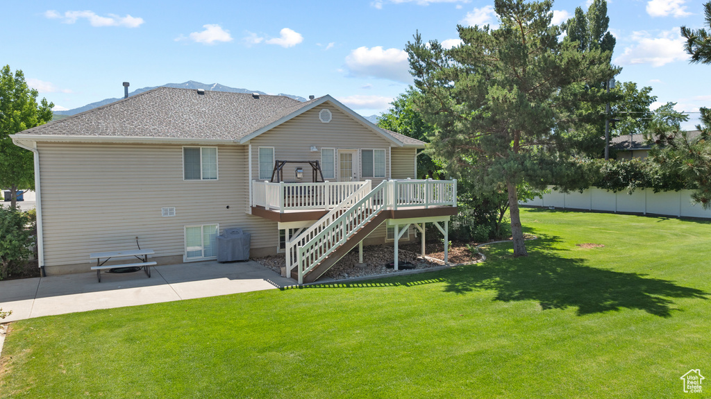 Rear view of house with a deck, a patio, stairway, and roof with shingles