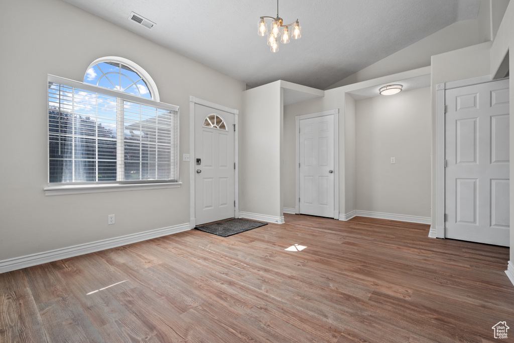 Entryway featuring a chandelier, lofted ceiling, and wood finished floors