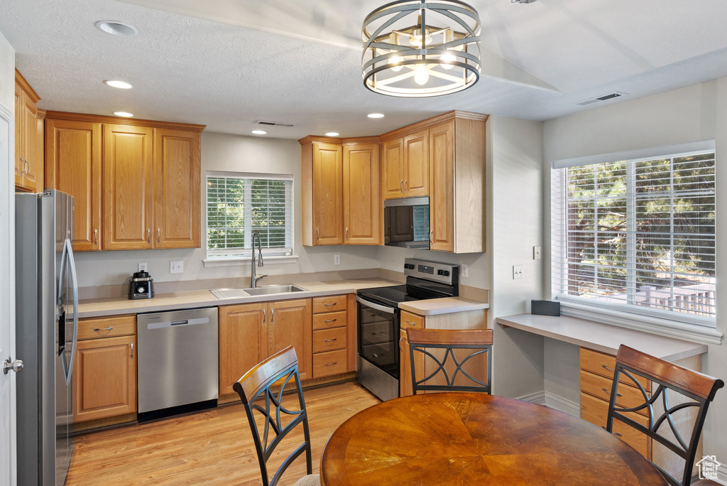 Kitchen featuring stainless steel appliances, light wood-style floors, light countertops, recessed lighting, and a chandelier