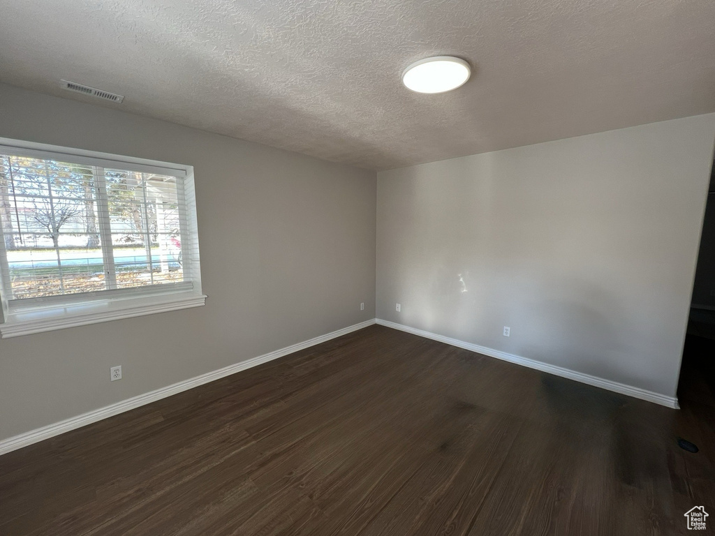Unfurnished room with dark wood-style flooring and a textured ceiling