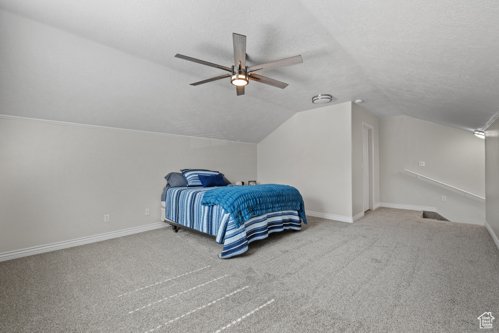 Carpeted bedroom featuring a textured ceiling, lofted ceiling, and a ceiling fan