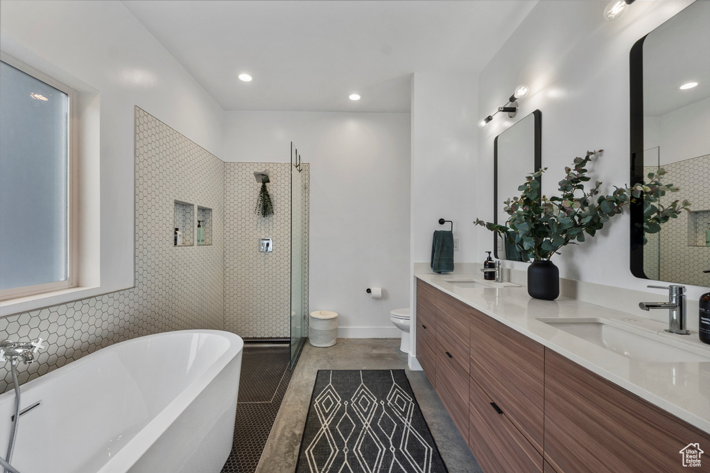 Full bathroom with double vanity, tiled shower, a freestanding tub, and recessed lighting