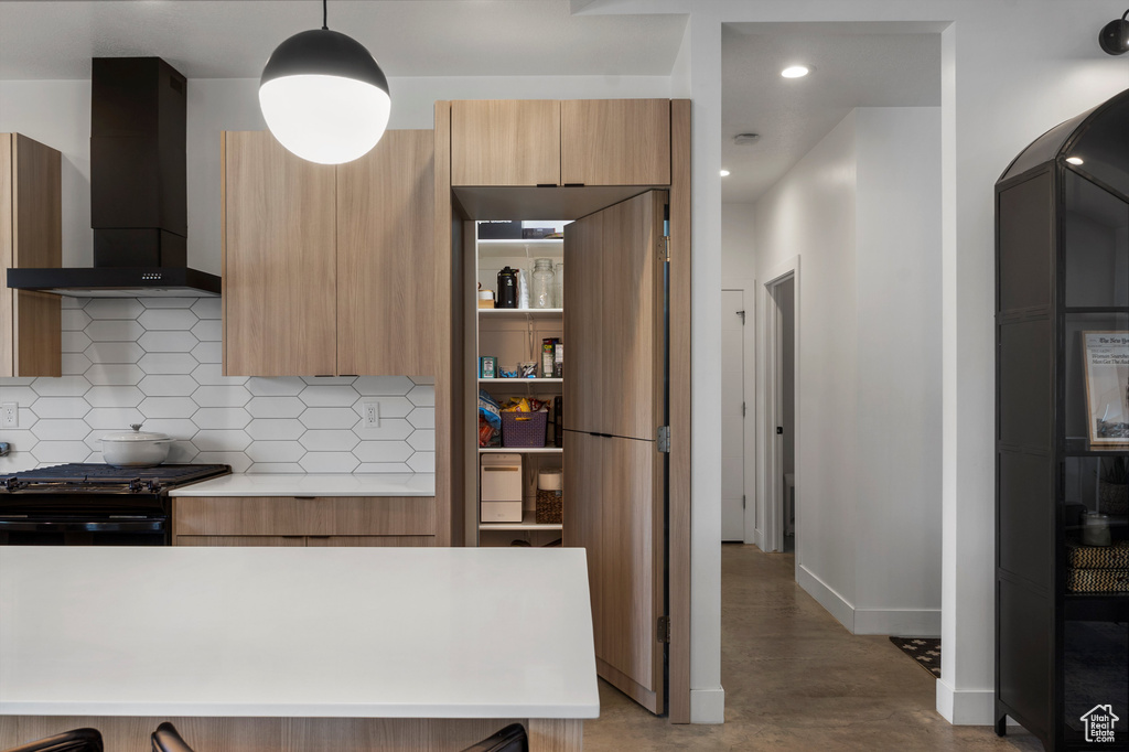 Kitchen with wall chimney exhaust hood, light countertops, backsplash, modern cabinets, and recessed lighting
