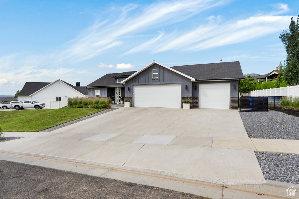 View of front of house featuring board and batten siding, an attached garage, driveway, and brick siding
