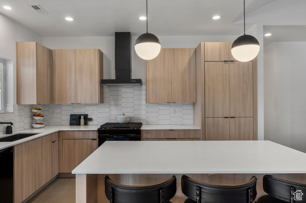 Kitchen with wall chimney exhaust hood, modern cabinets, black appliances, a breakfast bar, and recessed lighting
