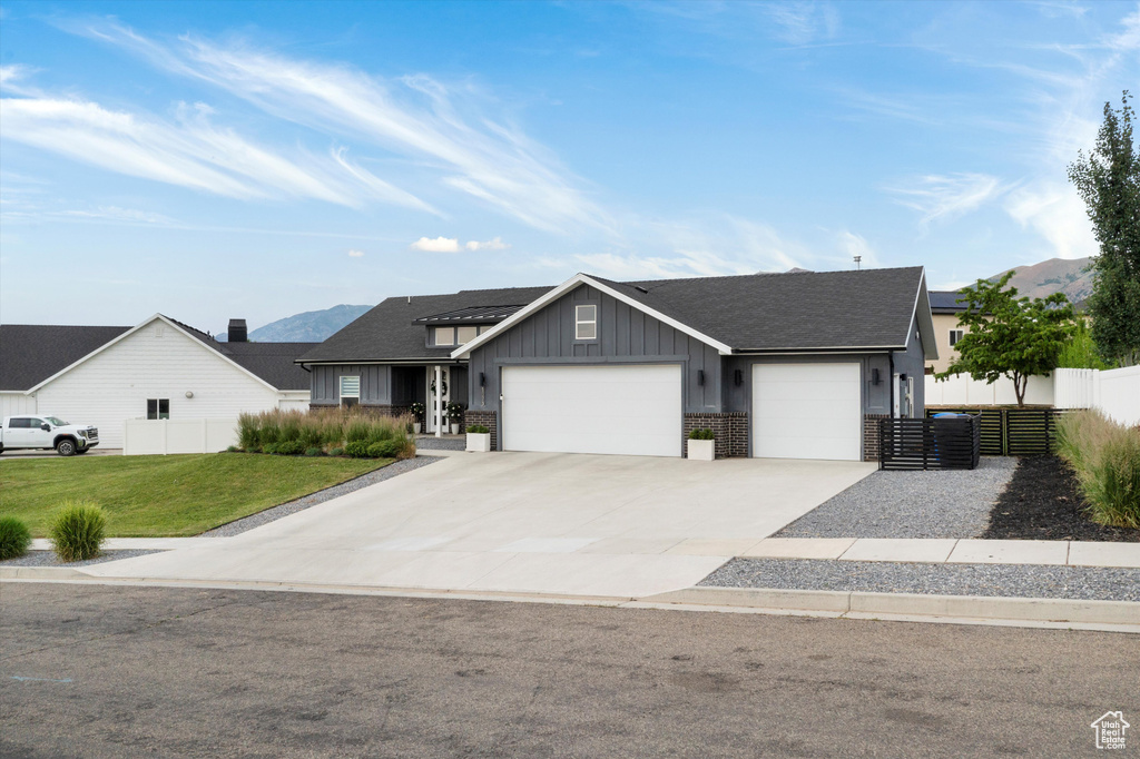 View of front of home with board and batten siding, an attached garage, driveway, and a shingled roof