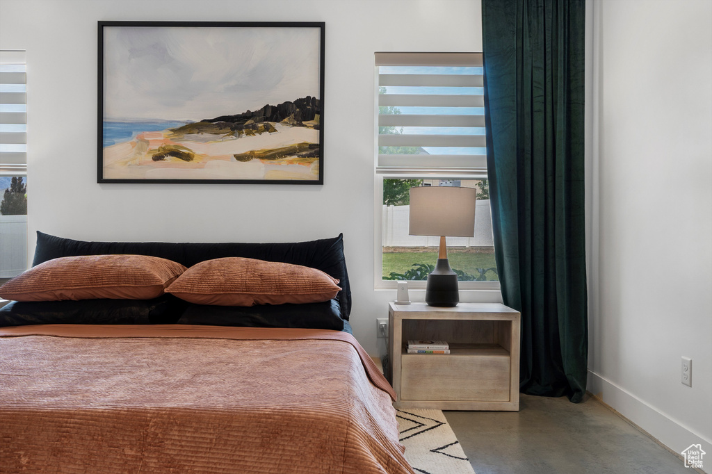 Bedroom featuring multiple windows and finished concrete flooring