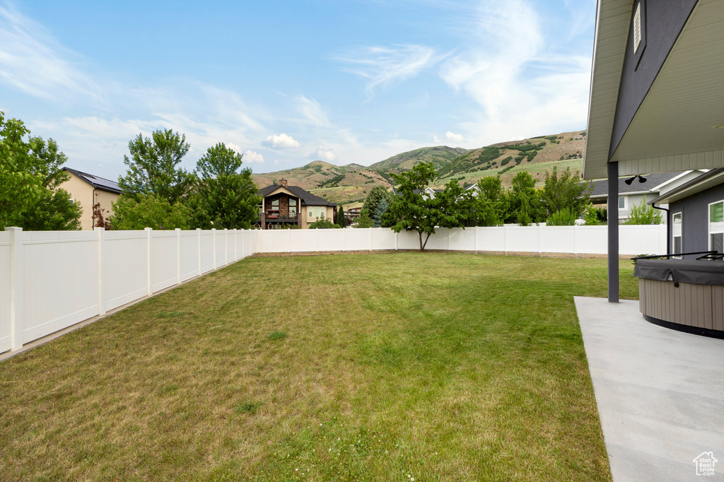 Fenced backyard with a hot tub, a mountain view, and a patio