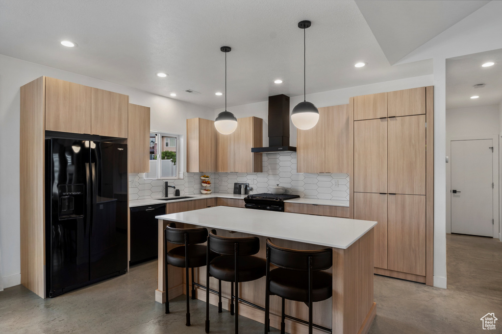 Kitchen with black appliances, wall chimney range hood, modern cabinets, a breakfast bar, and recessed lighting