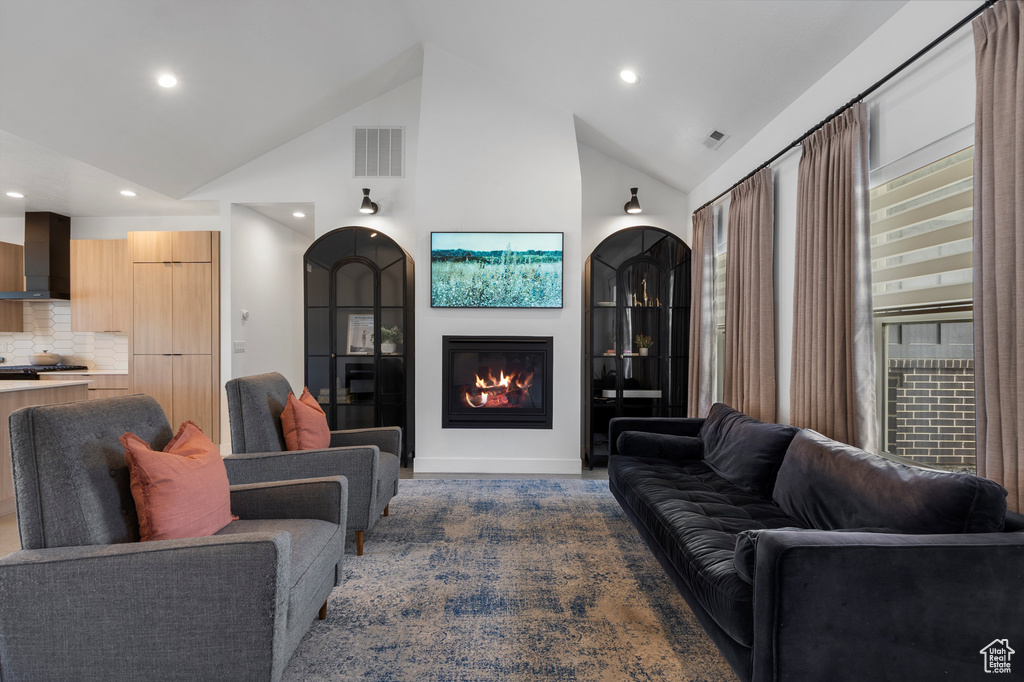 Living room featuring recessed lighting, a glass covered fireplace, and high vaulted ceiling