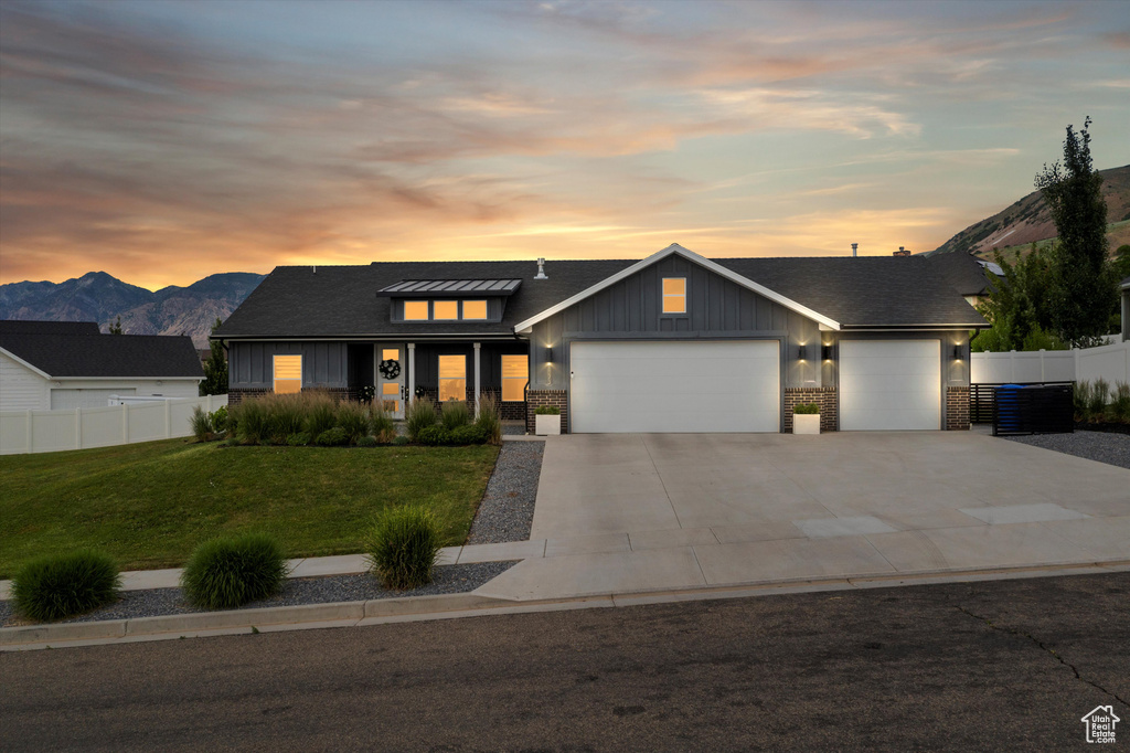 View of front of home featuring a garage, board and batten siding, concrete driveway, a mountain view, and brick siding
