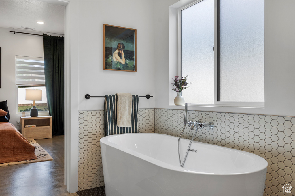 Full bathroom with tile walls, a soaking tub, wainscoting, and recessed lighting