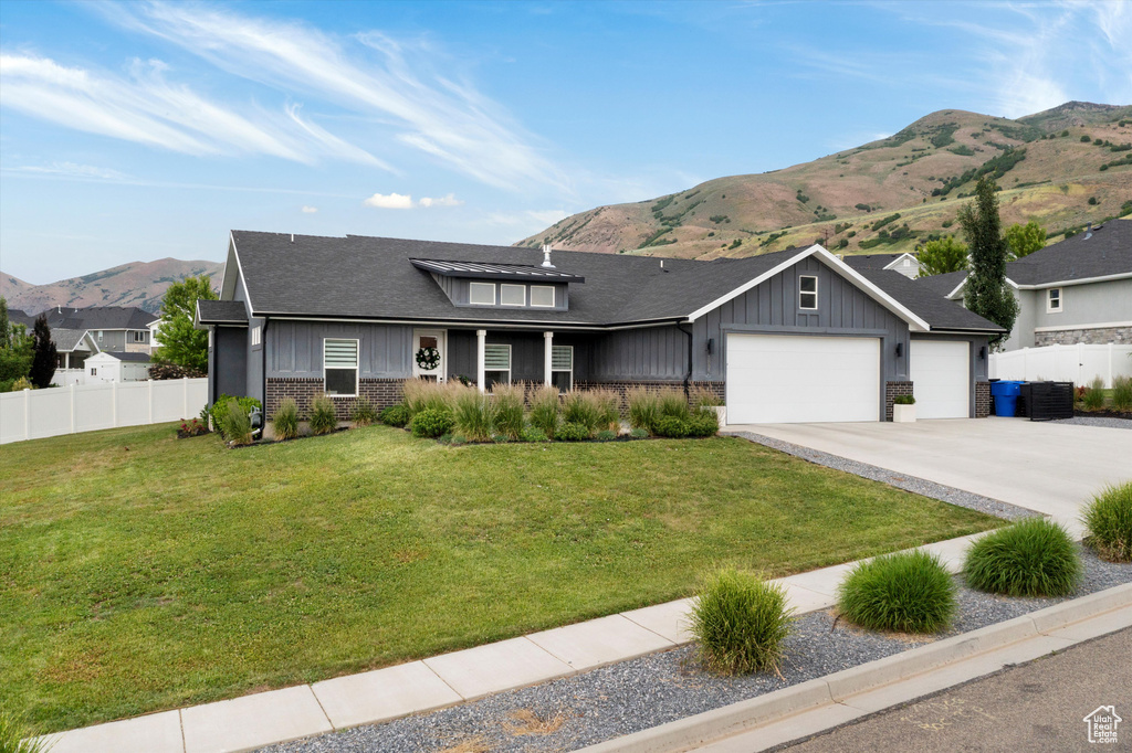 View of front of home featuring board and batten siding, a mountain view, an attached garage, and brick siding