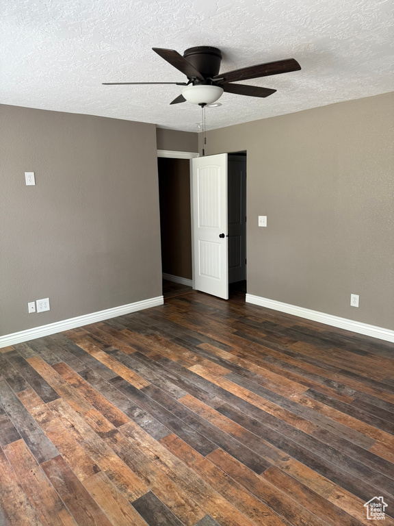 Unfurnished room with a ceiling fan, dark wood-type flooring, and a textured ceiling