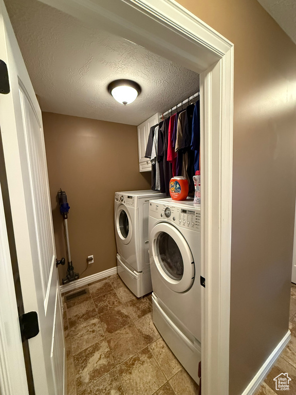 Washroom with washer and dryer and a textured ceiling