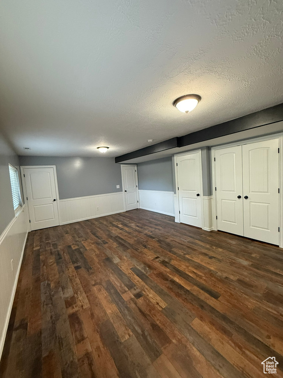 Below grade area featuring wood finished floors, a wainscoted wall, and a textured ceiling
