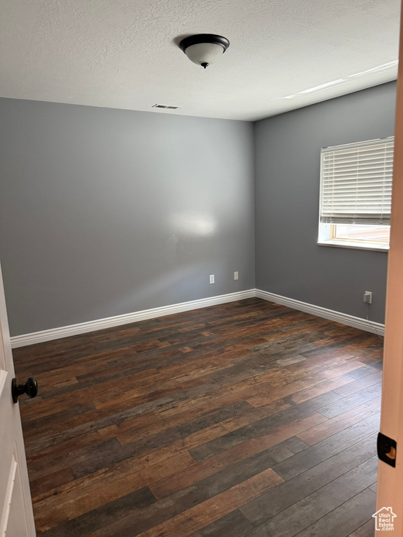 Spare room with dark wood-type flooring and baseboards