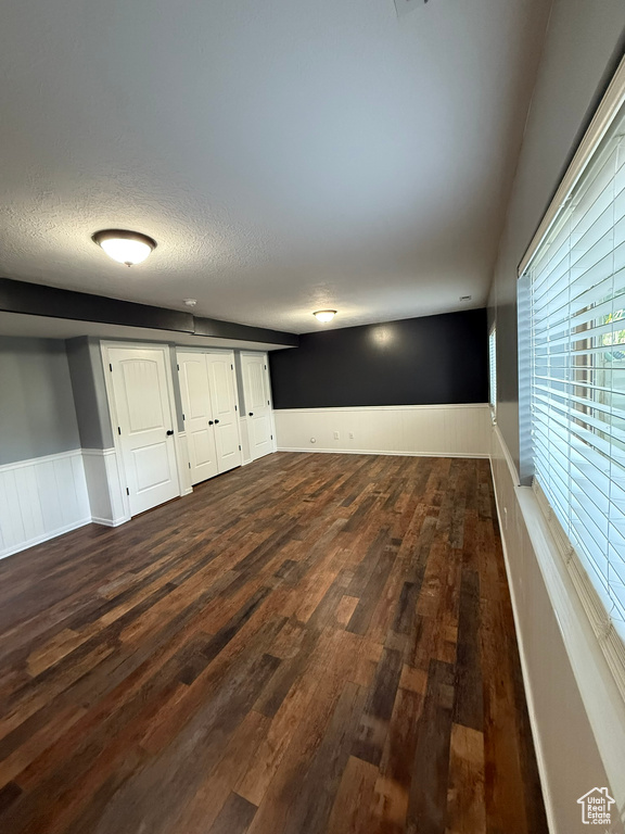 Unfurnished room featuring a wainscoted wall, dark wood-style floors, and a textured ceiling