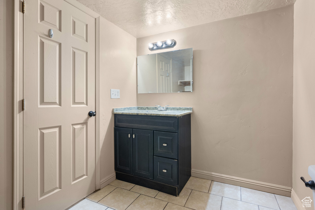 Bathroom with vanity, a textured ceiling, and tile patterned floors