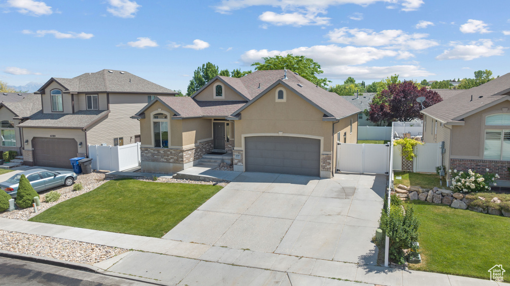 View of front of home featuring stucco siding, a gate, a garage, concrete driveway, and stone siding