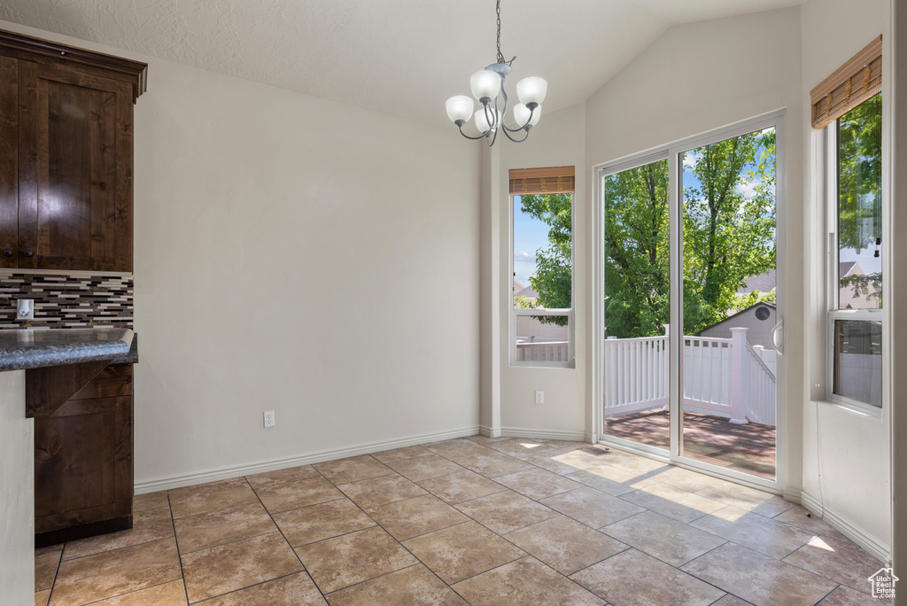 Unfurnished dining area featuring vaulted ceiling and a chandelier
