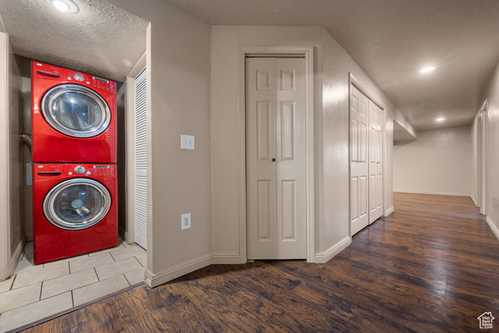 Washroom featuring stacked washer / dryer, wood finished floors, and recessed lighting