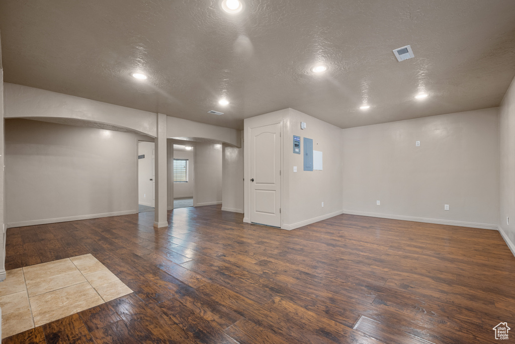 Basement with a textured ceiling, hardwood / wood-style floors, arched walkways, and recessed lighting