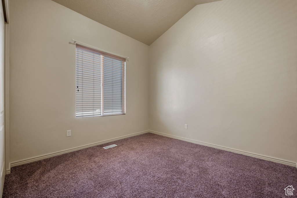 Spare room with vaulted ceiling and carpet flooring