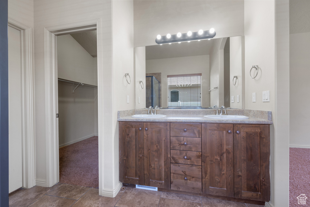 Full bath with double vanity, a spacious closet, and a shower with shower door