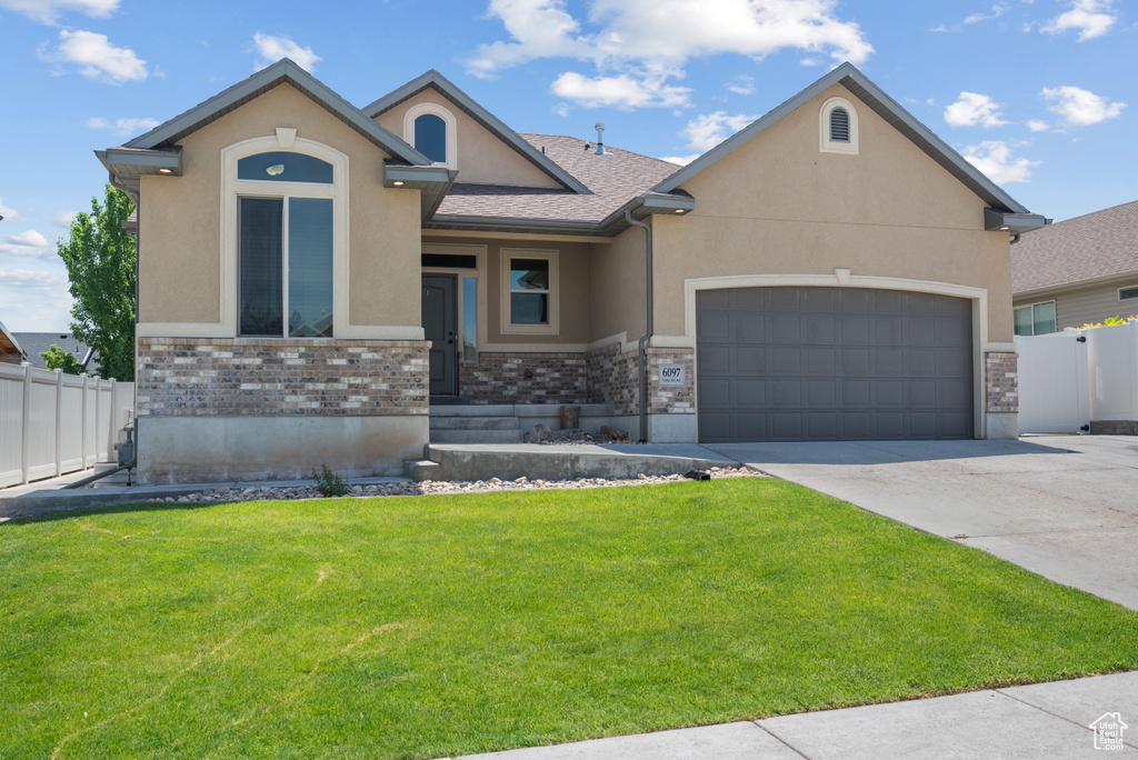 View of front of home with stucco siding, an attached garage, concrete driveway, and stone siding