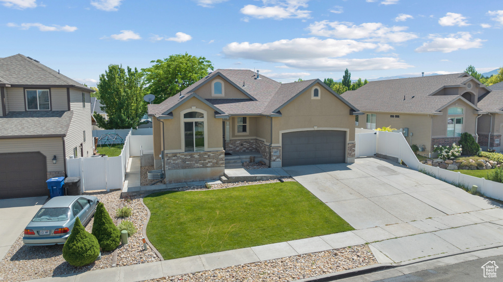View of front of house with stucco siding, driveway, a garage, a gate, and stone siding