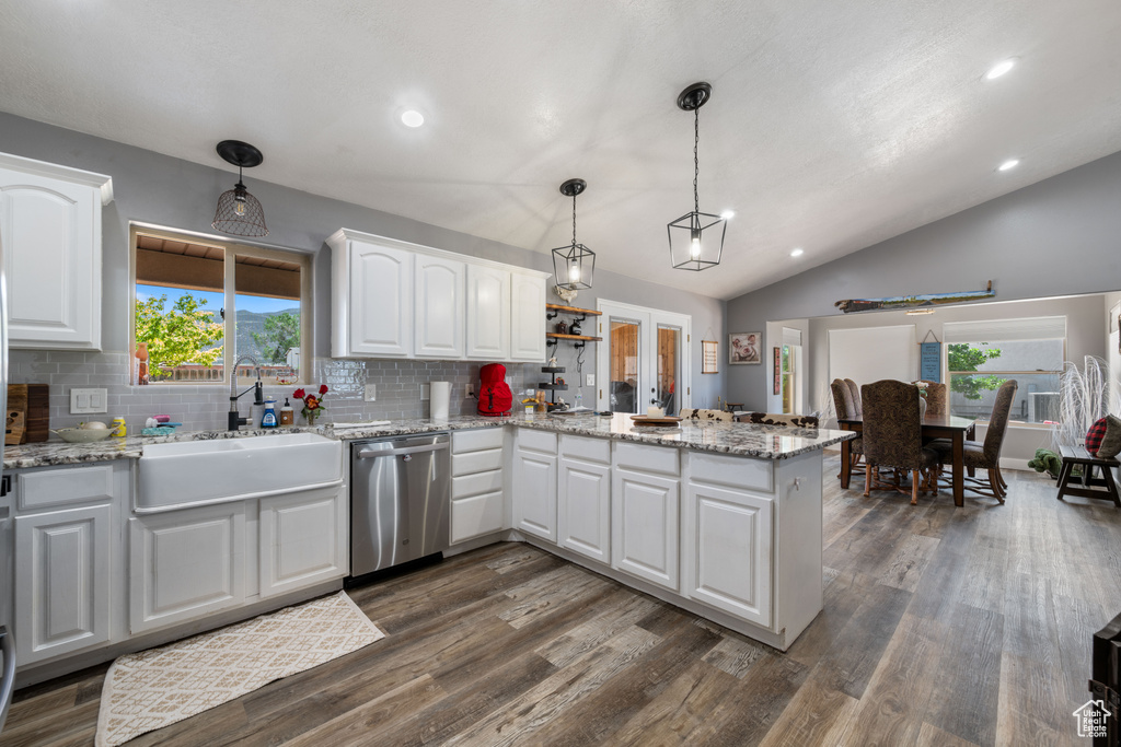 Kitchen featuring stainless steel dishwasher, a peninsula, tasteful backsplash, white cabinets, and pendant lighting