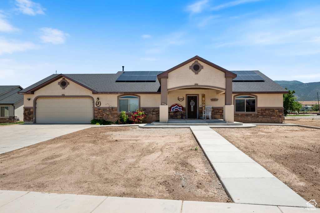 View of front of property with stone siding, stucco siding, and solar panels