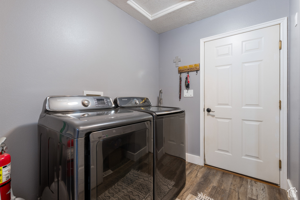 Washroom featuring washing machine and clothes dryer, dark wood-style floors, attic access, and a textured ceiling