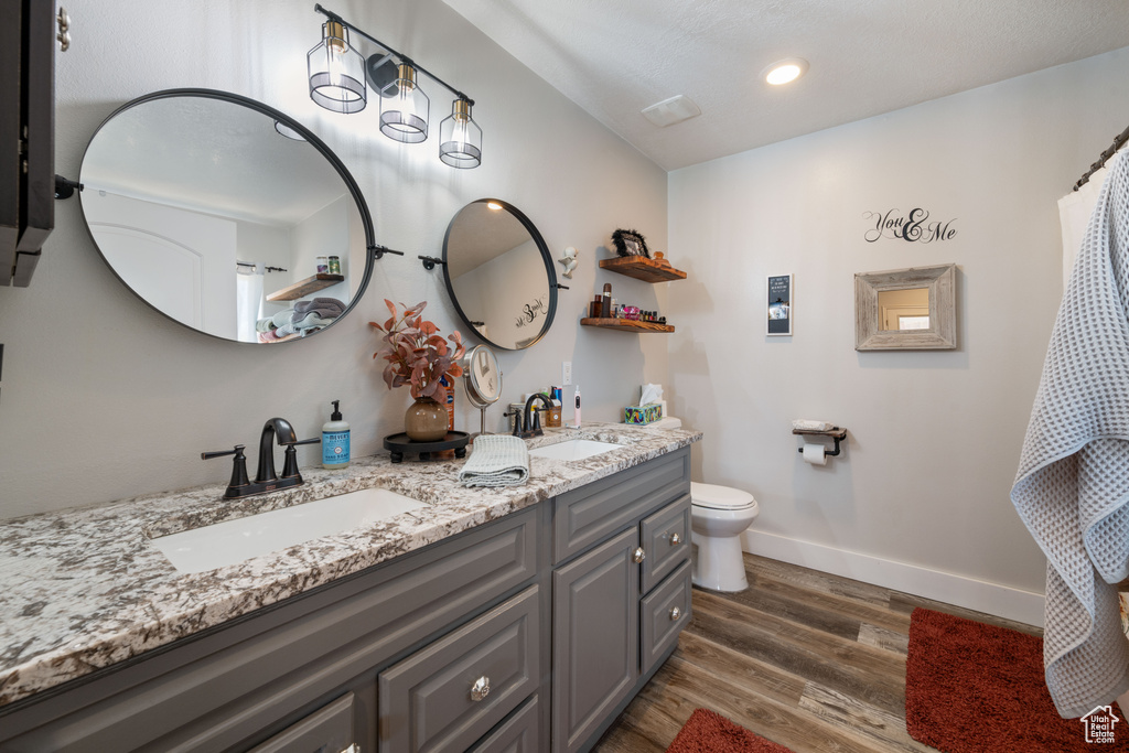 Full bath featuring double vanity, wood finished floors, and recessed lighting