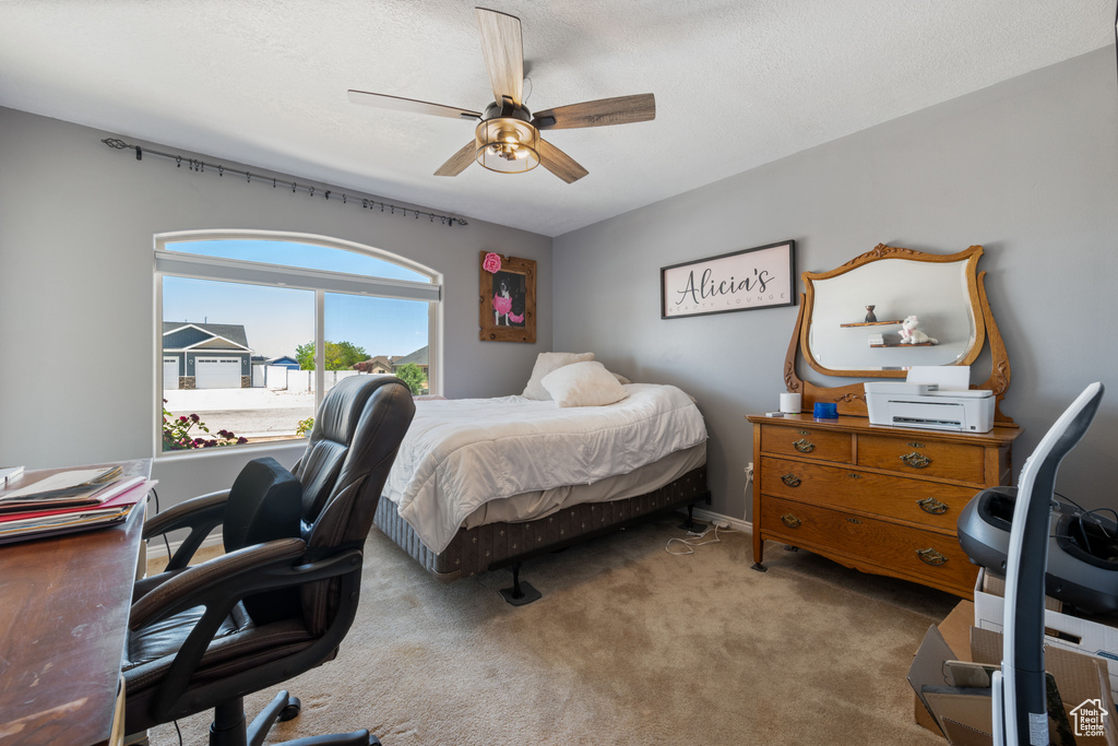 Bedroom with an office area, carpet, and a ceiling fan