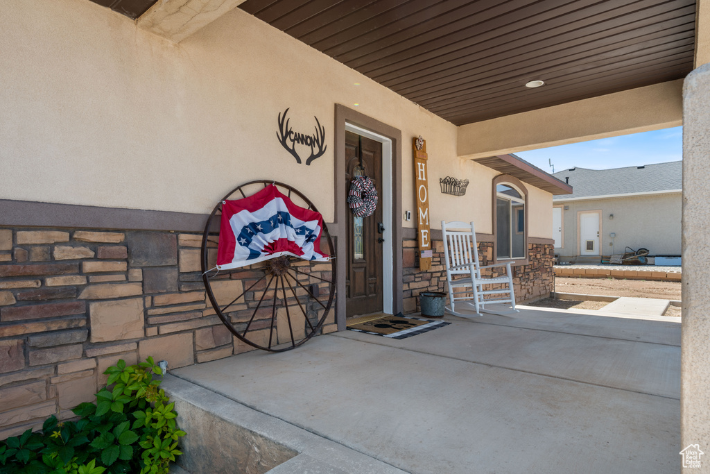 View of exterior entry featuring stucco siding, stone siding, and covered porch
