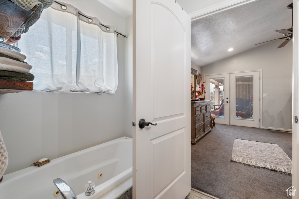 Bathroom featuring a whirlpool tub, lofted ceiling, a ceiling fan, and french doors