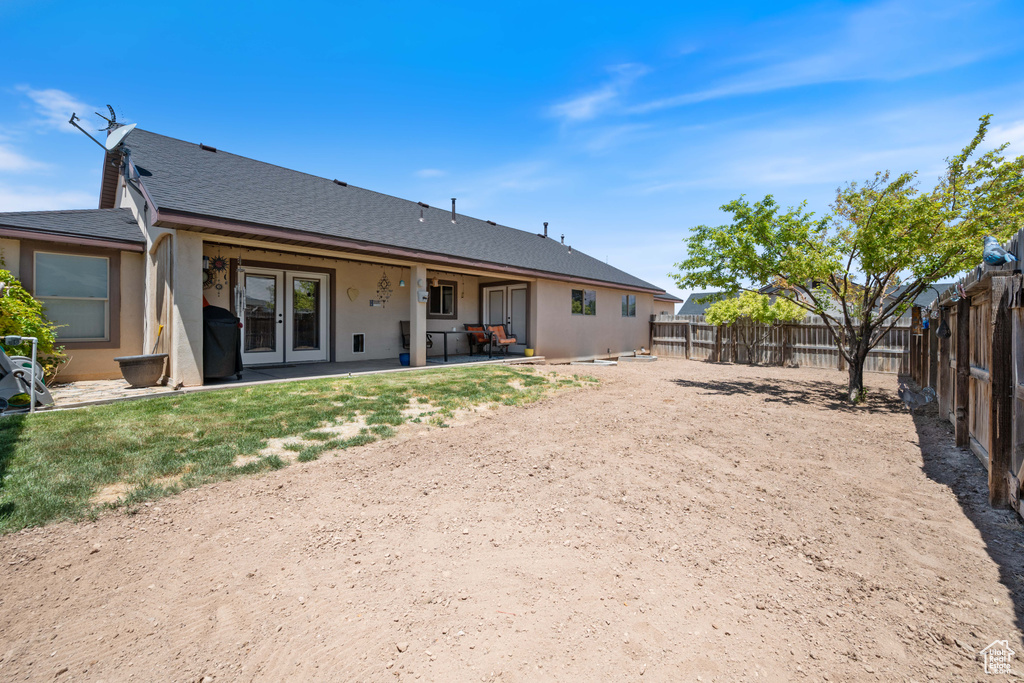 Back of house featuring a fenced backyard, a patio area, roof with shingles, stucco siding, and french doors