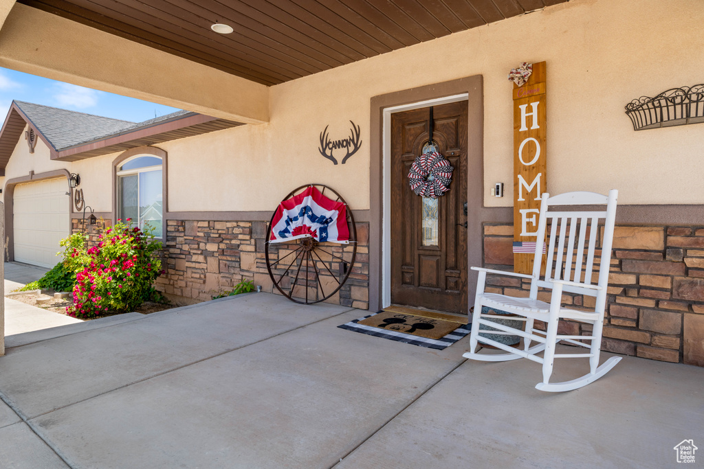 Property entrance featuring stone siding, stucco siding, and a garage