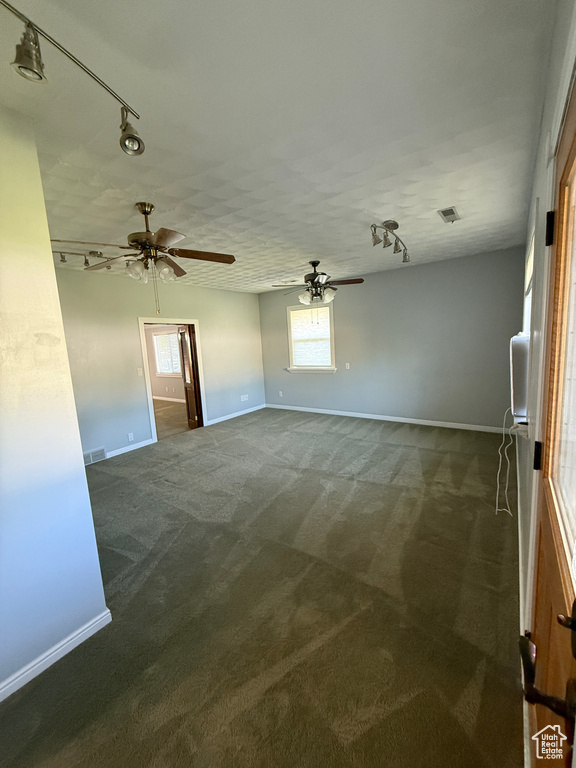 Unfurnished room featuring rail lighting, carpet floors, a ceiling fan, and plenty of natural light