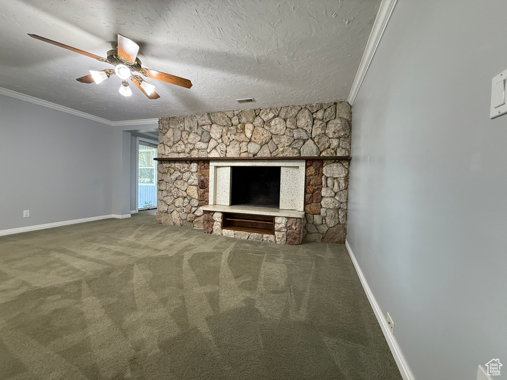 Unfurnished living room with crown molding, a ceiling fan, carpet floors, a fireplace, and a textured ceiling