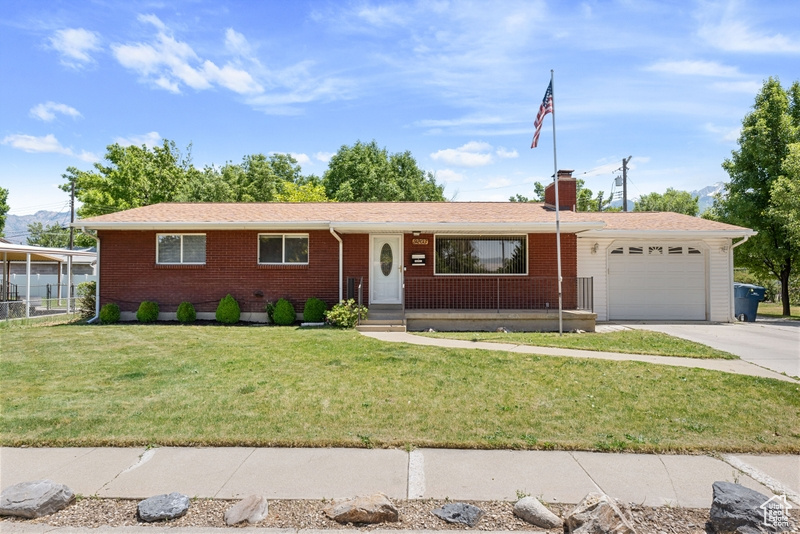 Single story home featuring a garage, brick siding, concrete driveway, and a front yard