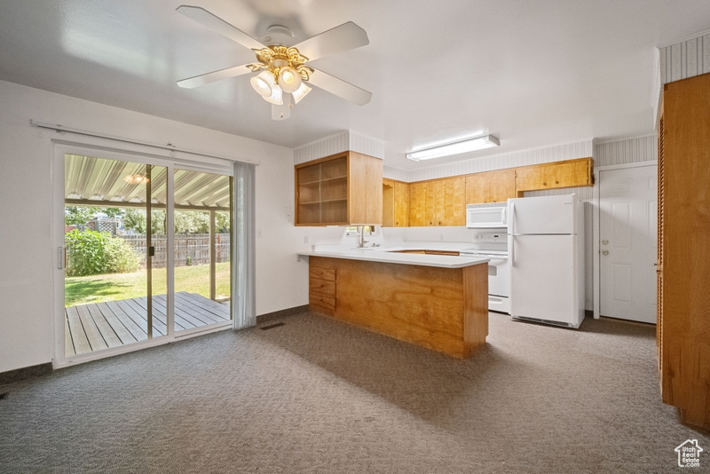 Kitchen featuring white appliances, a peninsula, carpet floors, open shelves, and a ceiling fan