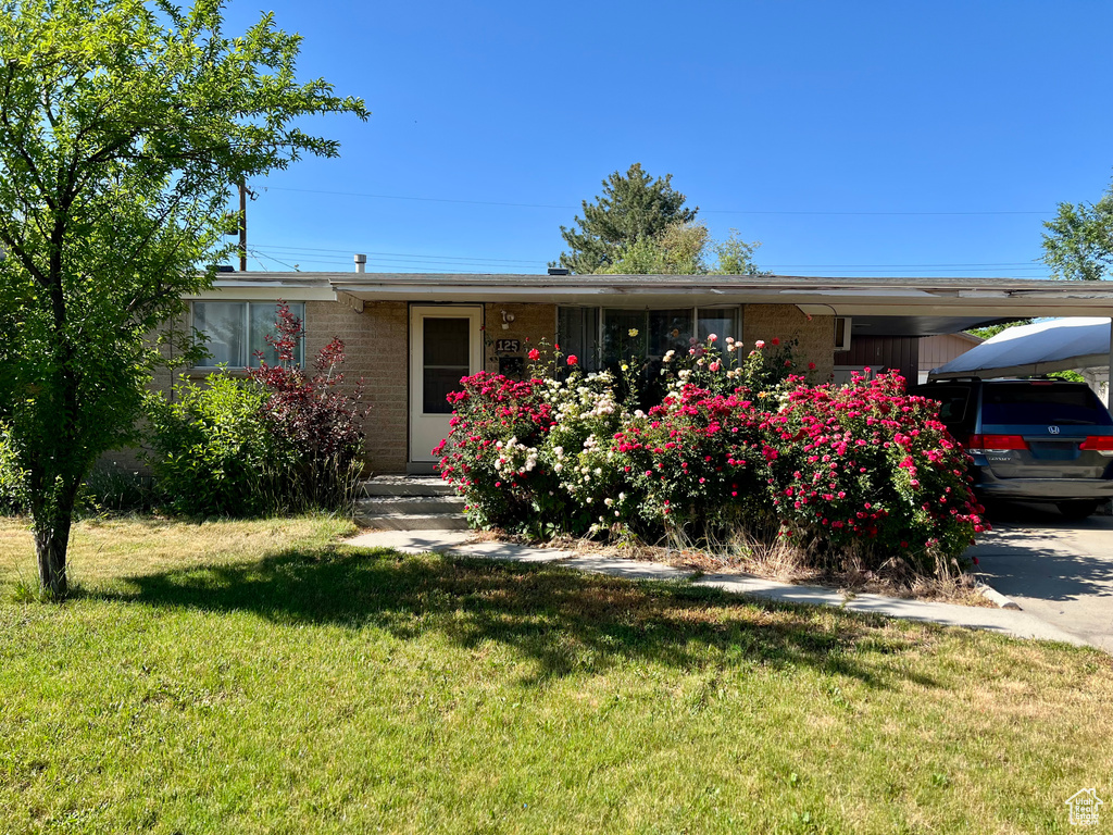 Single story home featuring brick siding, a front lawn, and an attached carport