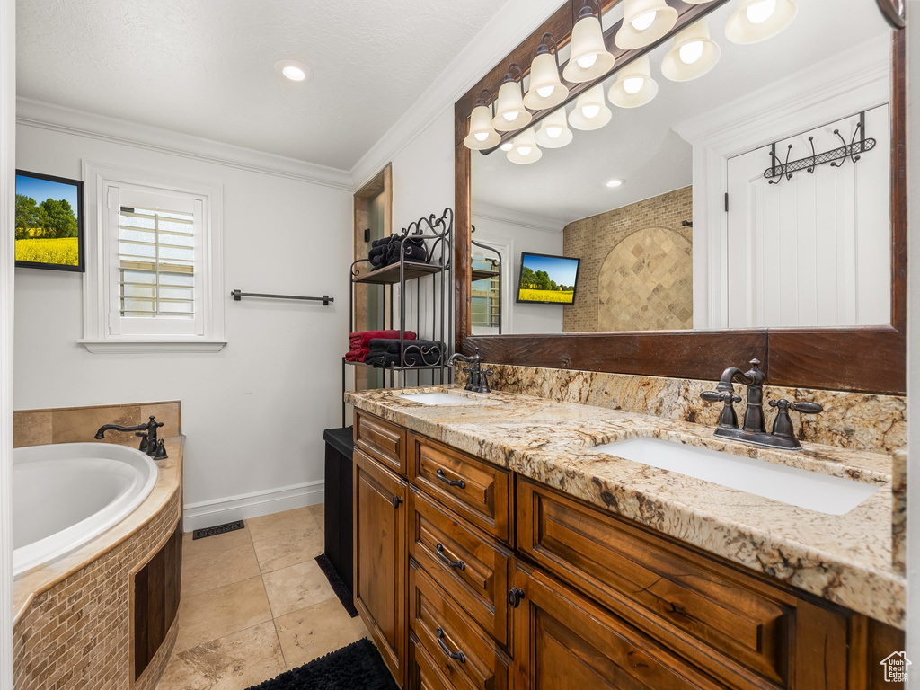 Full bath featuring double vanity, a bath, ornamental molding, and tile patterned floors