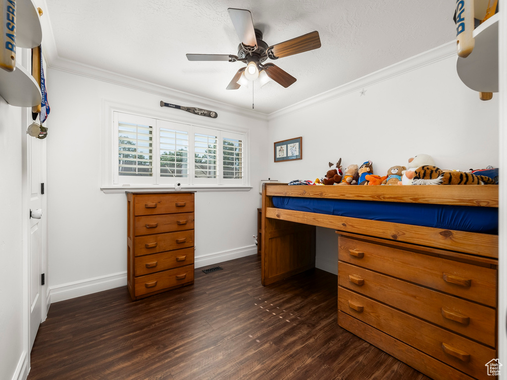 Bedroom with a desk, dark wood-style floors, ornamental molding, and a ceiling fan