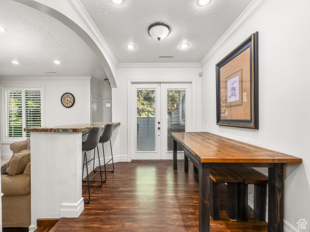 Interior space with a textured ceiling, arched walkways, plenty of natural light, dark wood-type flooring, and french doors