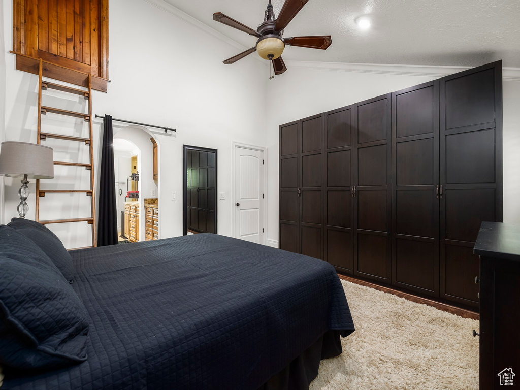 Bedroom featuring arched walkways, high vaulted ceiling, ornamental molding, and ceiling fan