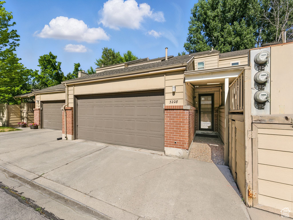 View of front of home with brick siding, an attached garage, and driveway